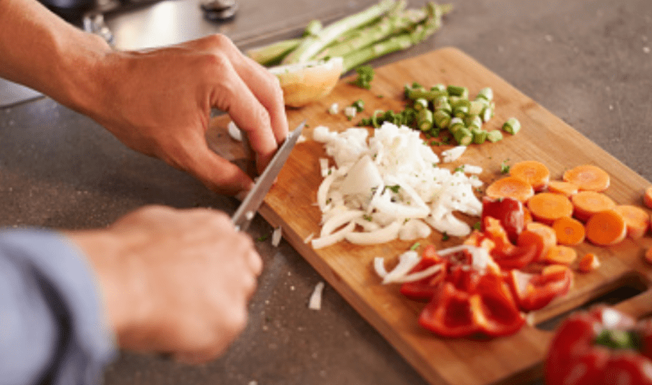 Man cutting vegetables on a wooden cutting board