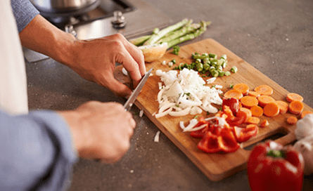 Man cutting vegetables on a wooden cutting board